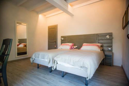 Agriturismo Bellarosa في Albinea: غرفة نوم بسرير كبير مع شراشف بيضاء ومخدات حمراء