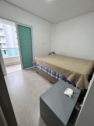 a bedroom with a bed and a table and a window at Vista Panorâmica Enseada in Guarujá