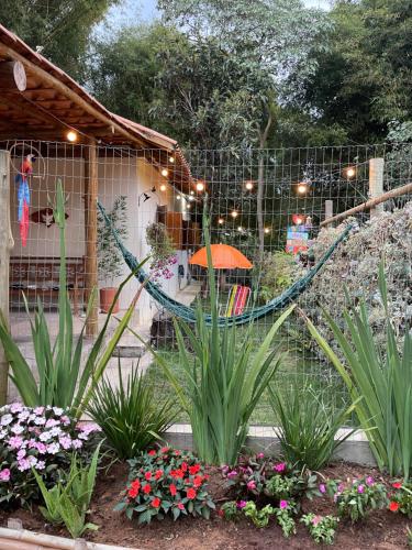 a hammock in a garden with flowers and plants at Chale Pepe in Carrancas