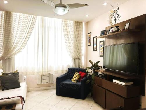 a living room with a flat screen tv and a chair at Charme do Leme in Rio de Janeiro