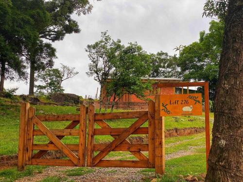 a wooden gate with a sign on it next to a tree at LOFT.276 - CASA DE CAMPO in Bento Gonçalves