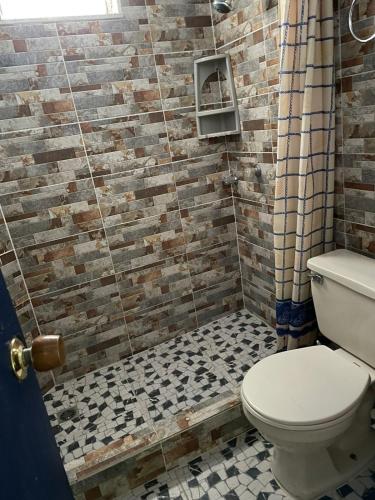 a bathroom with a toilet and a brick wall at Itaca Hostel finca Cafetera in Belalcázar