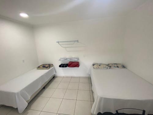 Duas camas num quarto com paredes brancas em Pousada Helena e Heloá em Serra Negra