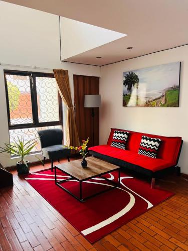 sala de estar con sofá rojo y alfombra roja en Duplex en primer piso - A media Cuadra Embajada USA, en Lima