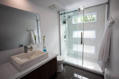 a bathroom with a sink and a glass shower at Parc de l'Île Melville 2 - Maison flottante in Shawinigan