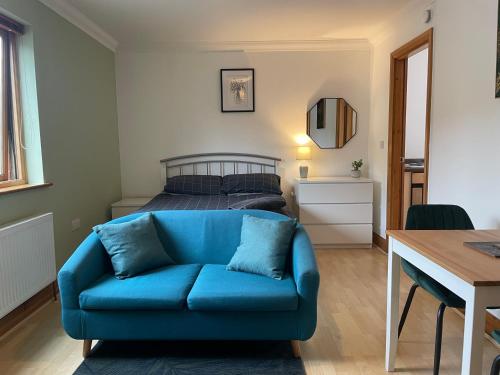 uma sala de estar com um sofá azul em frente a uma cama em Lovely Studio Apartment in the Center of Norwich em Norwich