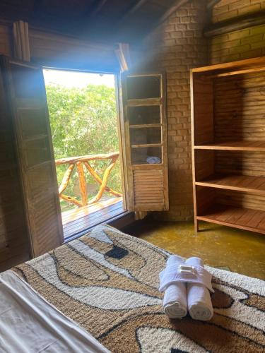 ein Zimmer mit einem Bett mit einem Teppich und einem Fenster in der Unterkunft Pousada Chalés Vale do Sol in Conceição da Ibitipoca