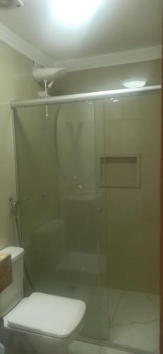 a bathroom with a toilet and a glass shower at Flat Ilhéus - Jubiabá Olivença in Ilhéus