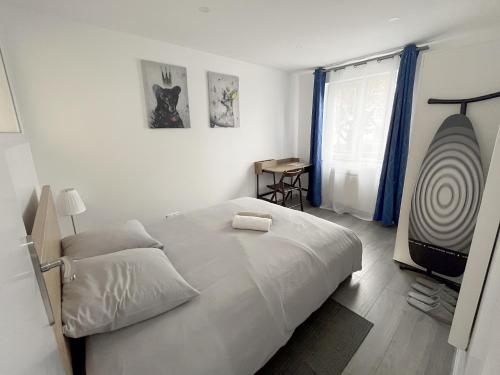 a white bedroom with a bed and a window at Le petit chic in Vaucresson