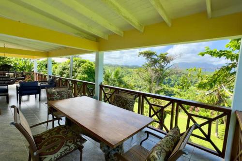 a table and chairs on a balcony with a view at LaCaye - Home in Creole in Calibishie