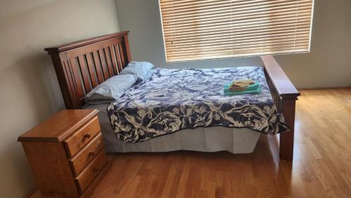Beeliar Shared Home Stay في Coogee: سرير في غرفة نوم مع أرضية خشبية