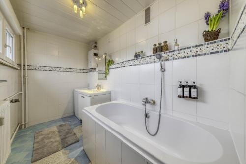 uma casa de banho branca com uma banheira e um lavatório em Appartement Les Oiseaux em Thionville