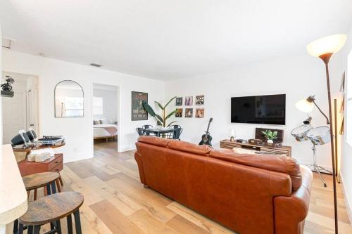 a living room with a brown leather couch and a tv at Musicians Lounge - 2 BR with parking asssigned in Fort Lauderdale