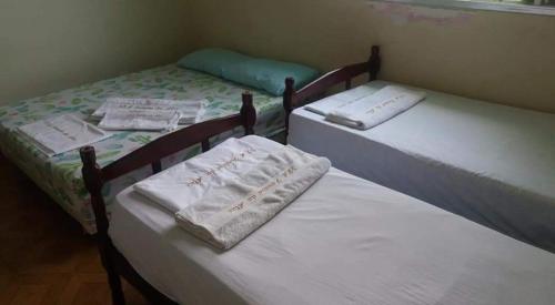 Dos camas en una habitación con toallas. en Pousada pé na areia em Mongaguá en Mongaguá