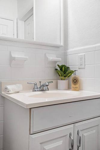 a white bathroom with a sink and a mirror at Musicians Lounge - 2 BR with parking asssigned in Fort Lauderdale