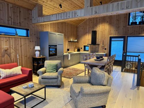 a living room with chairs and tables and a kitchen at Ny hytte, fantastisk utsikt rett ved Vestlia in Geilo