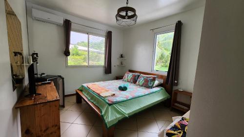 a bedroom with a bed in a room with two windows at La Maison Orange in Moorea