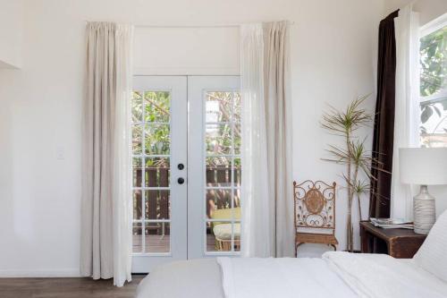 a white bedroom with a bed and a sliding glass door at Take it easy on the porch in a Hollywood hideaway in Los Angeles