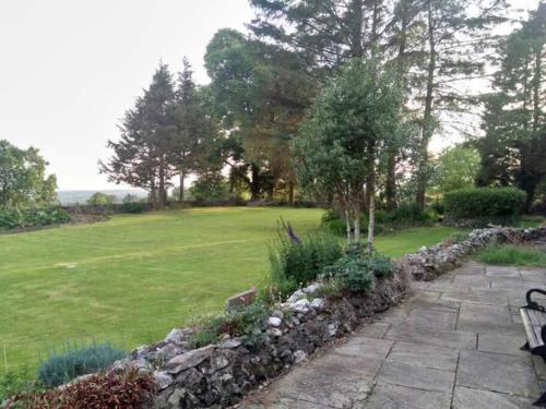 a garden with a stone wall and a bench at 3 Tan Y Coed in Brynkir