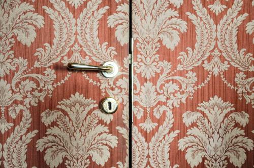 a wooden door with a handle on a wall with wallpaper at Ca' Amadi in Venice
