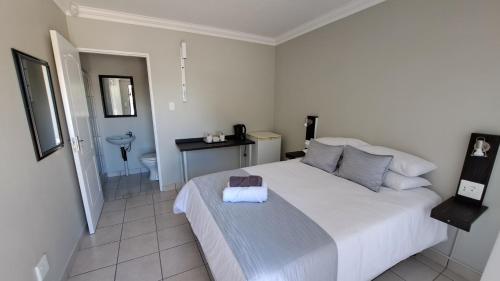 a bedroom with a large white bed and a bathroom at Chrisserus Guest Rooms in Bloemfontein