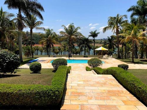 a resort with a swimming pool and palm trees at Linda Chácara em Piracaia SP in Piracaia