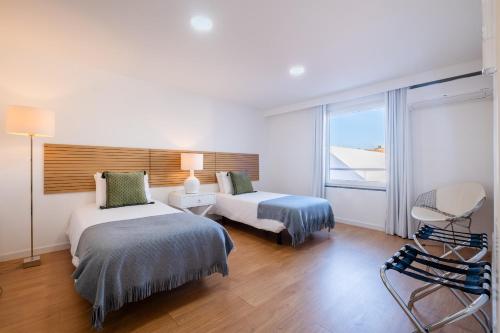 a hotel room with two beds and a window at Ponta Delgada Flats - HOST & CHILL in Ponta Delgada