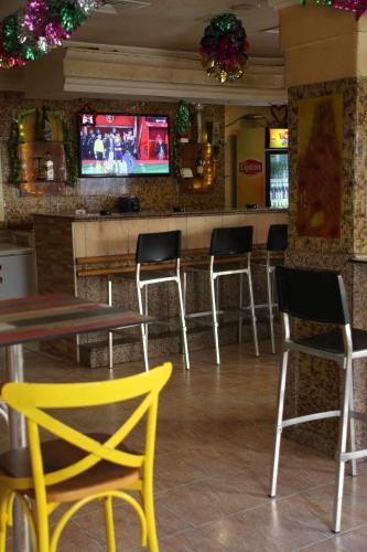 a restaurant with chairs and a bar with televisions at Hotel Amine in Sfax