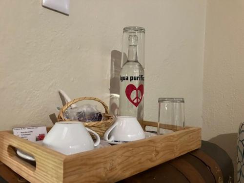 a wooden tray with a bottle and cups and a basket at Hotel Amor y Paz in Real de Catorce