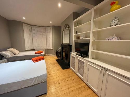 a bedroom with two beds and a tv and shelves at Home in Greenwich near the O2 in London