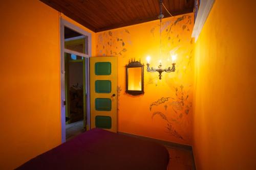 a bedroom with an orange wall with a chandelier at Soul - moradia criativa in Vila Franca de Xira