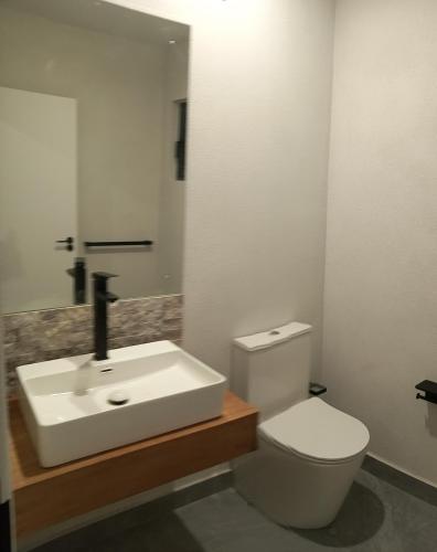 a bathroom with a white sink and a toilet at Sanctuary Villa in Christ Church