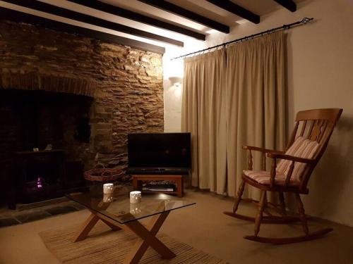 a living room with a chair and a television at Cosy private cottage near beach in Ilfracombe