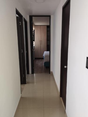 a hallway with black doors and a bed in a room at apartamento cerca al aeropuerto parqueadero privado conjunto cerrado bilbao in Cúcuta