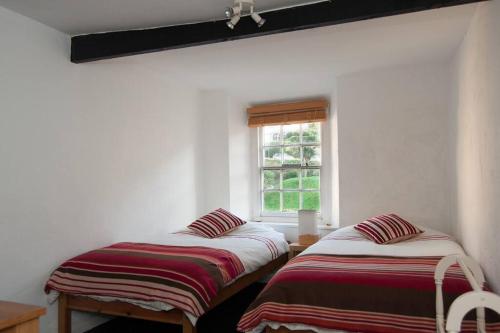 zwei Betten in einem Zimmer mit Fenster in der Unterkunft Cosy private cottage near beach in Ilfracombe
