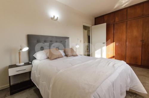 um quarto com uma grande cama branca e armários de madeira em NO - Durand em Assunção