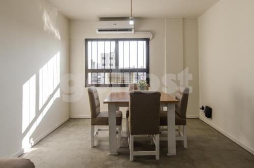 uma sala de jantar com uma mesa e cadeiras e uma janela em NO - Durand em Assunção