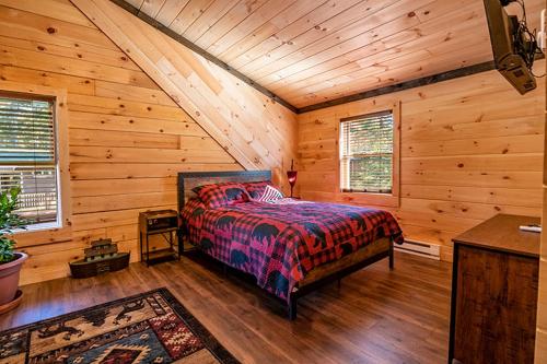 1 dormitorio con 1 cama en una cabaña de madera en Downhill Lodge, en Lake Placid