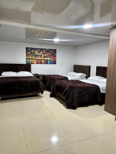 a bedroom with two beds and a painting on the wall at Amarena Hotel Boutique in Manizales