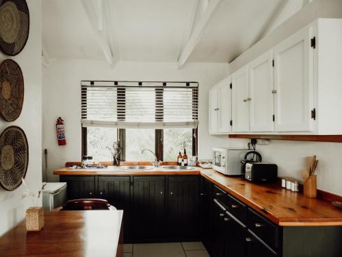a kitchen with white cabinets and a wooden counter top at Stanley Island in Plettenberg Bay