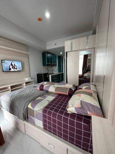 une chambre avec un grand lit et une télévision à écran plat dans l'établissement Sea View Studio Flat at Losari Beach, Makassar City, à Makassar