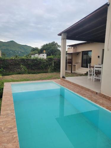 a blue swimming pool in front of a house at Casa con pileta en Vaqueros in Vaqueros