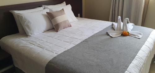 a large bed with white sheets and a flower on it at Pousada Vida de Rio in Neópolis