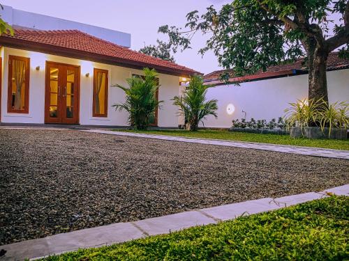 a house with a gravel driveway in front of it at Tiamo Bed & Breakfast in Matara