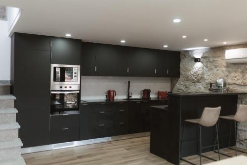 a kitchen with black cabinets and a stove top oven at Ahcor Housing - Quinta do Paço in Figueiredo de Alva