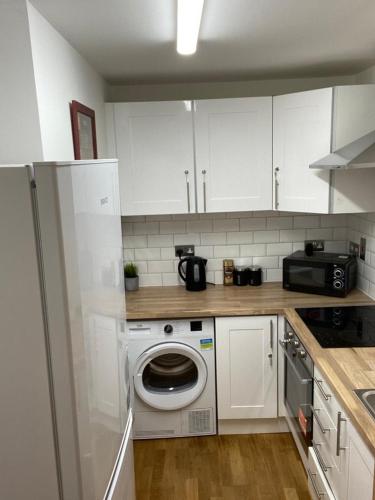 a kitchen with a washing machine and a microwave at Lovely Private Rooms in Euston, Central London in London