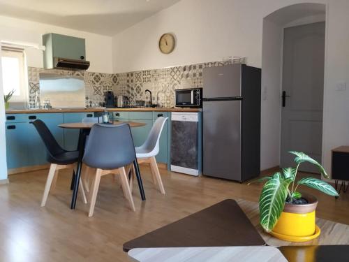 une cuisine avec une table, des chaises et un réfrigérateur dans l'établissement Le Petit d'Aquí appartement d'hôtes - 15 minutes de la mer, à Montblanc
