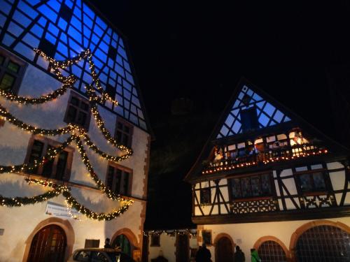 a christmas tree in front of two buildings with lights at Hotel KLE, BW Signature Collection in Kaysersberg
