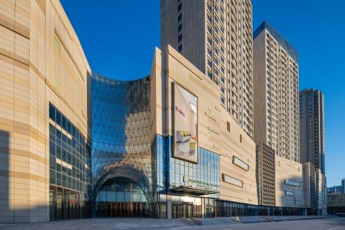 a tall building with glass windows in a city at Holiday Inn Express Weifang City Center by IHG in Weifang