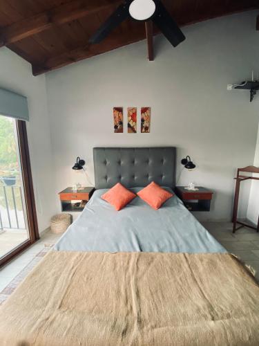 1 dormitorio con 1 cama grande y 2 almohadas de color naranja en Complejo Laguna Chica en Dique Luján